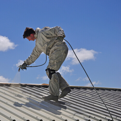 worker applying a metal roof coating