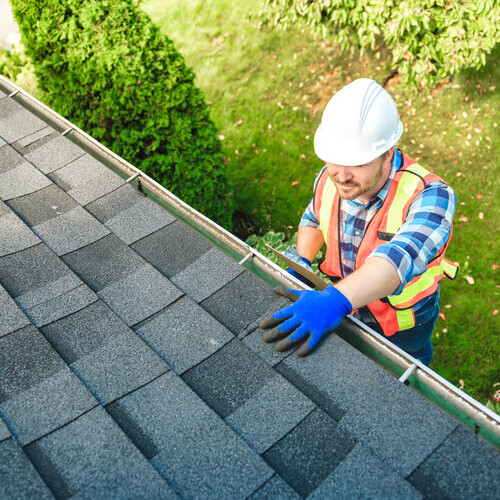 worker repairing a shingle roof